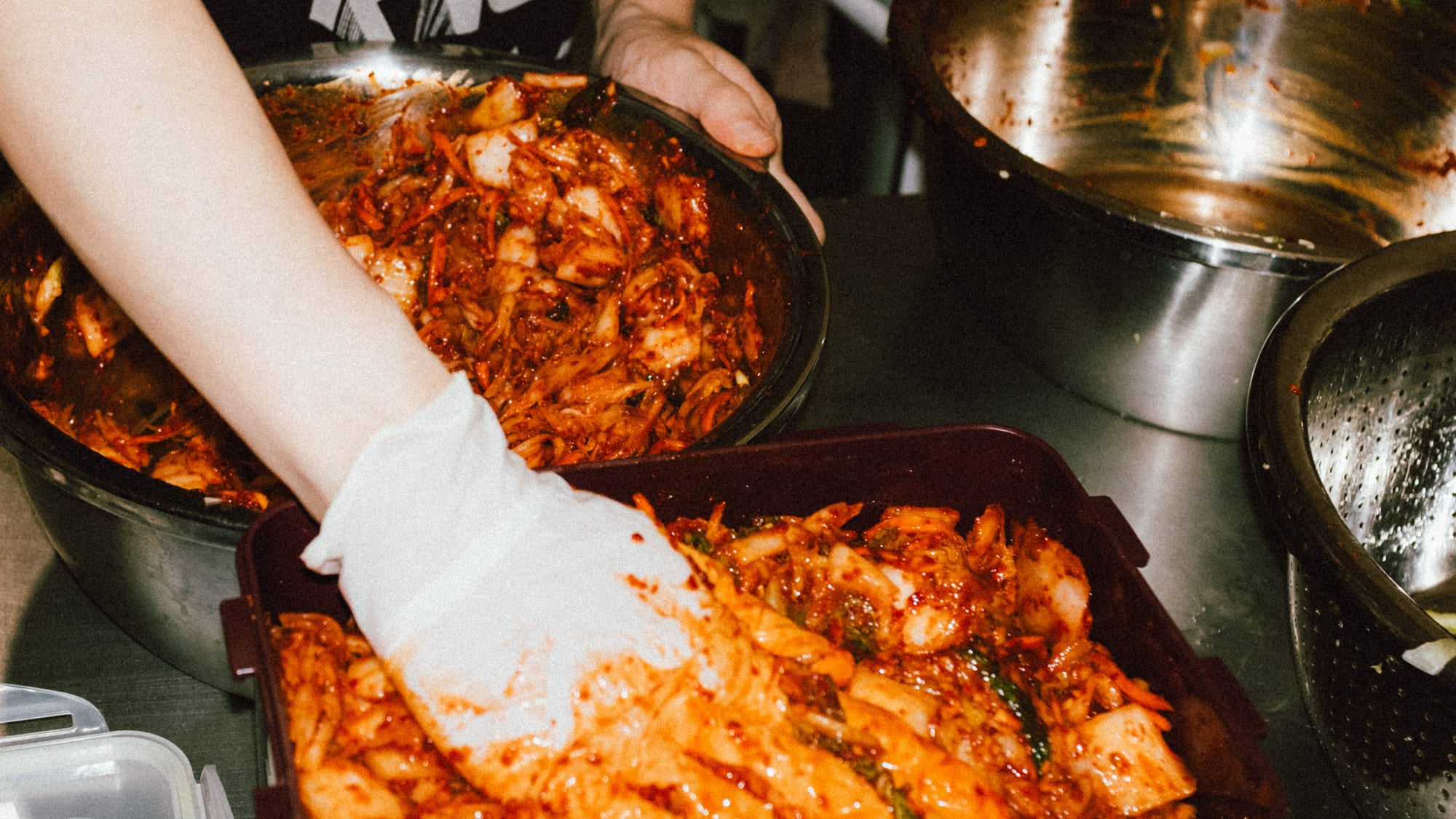 Kimchi being prepared by hand in the kitchen.
